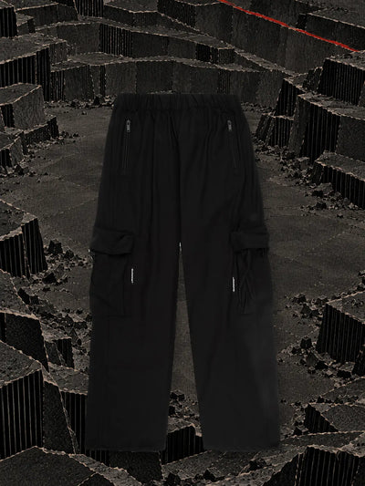 The black White Label cargo trousers at the bottom of a black cardboard quarry, with a red thread along the edge.