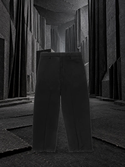 I pantaloni neri Classic in piedi in un corridoio di carta nera piegata a pieghe profonde, con una luce grigia dal fondo.
