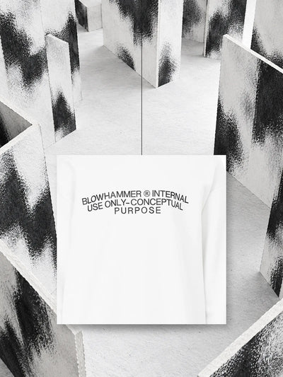 A piece of the white Concept crewneck sweatshirt with its printed lettering, hanging on a thread between white paper walls stained with black.