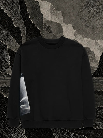 The black Core crewneck sweatshirt in a dark paper cave, in front of a panel of grey light in the smoke.