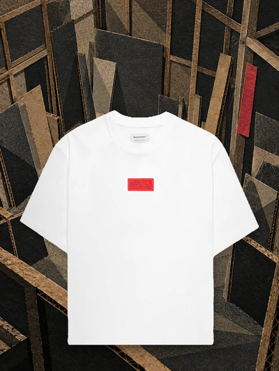 The white Deconstructed t-shirt in a cardboard workshop left half finished, among beams and leaning panels.