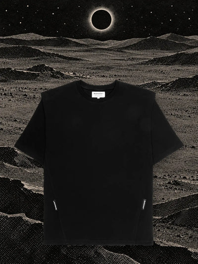 The black Eclipse t-shirt on hills of black paper, under an eclipse with a ring of white light.