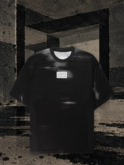 The black Leak t-shirt in a room of dark paper, with black ink dripping onto the floor in long streaks.