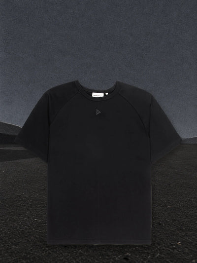 The black Minimal raglan t-shirt on a plain of black paper, with pale paper fog on the horizon.