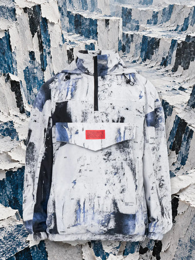 The white Rugged anorak between walls of torn white and blue paper.
