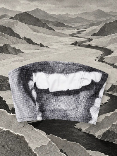 The grey and white Smile top in a valley of grey paper, near a dark river.