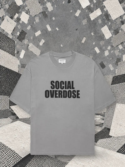 The grey Social Overdose t-shirt under a snowfall of small white and grey cards, over a landscape of paper blocks.