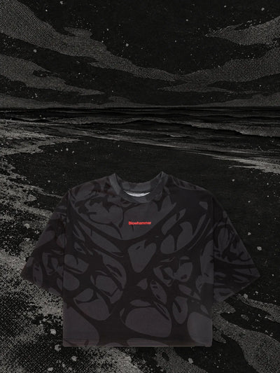 The cropped black Strand t-shirt on the bank of a black paper river, in the night.