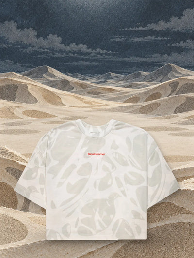 The cropped ivory Strand Ivory t-shirt above dunes of ivory and sand coloured paper.