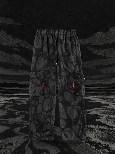 The black Strand cargo trousers on the bank of a black paper river, under a dark sky.