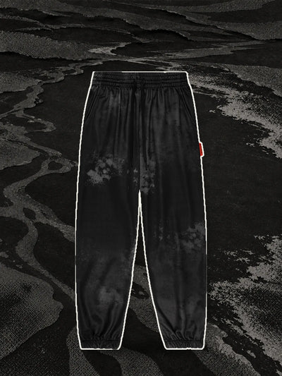 I joggers neri Strand, con un bordo di carta chiara, sulla riva di un fiume di carta nera a retino.