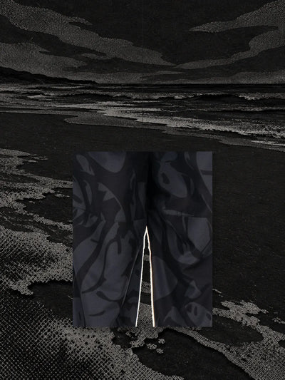 Un pezzo della stampa dei joggers neri Strand, appeso a un filo sopra la riva di un fiume di carta nera.