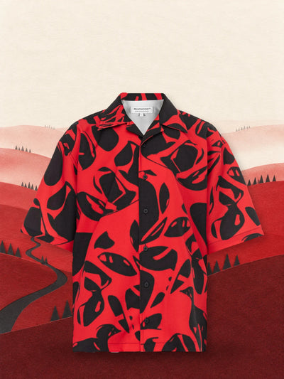 The red and black Strand Red short sleeve shirt among red paper hills, under a pale sky.