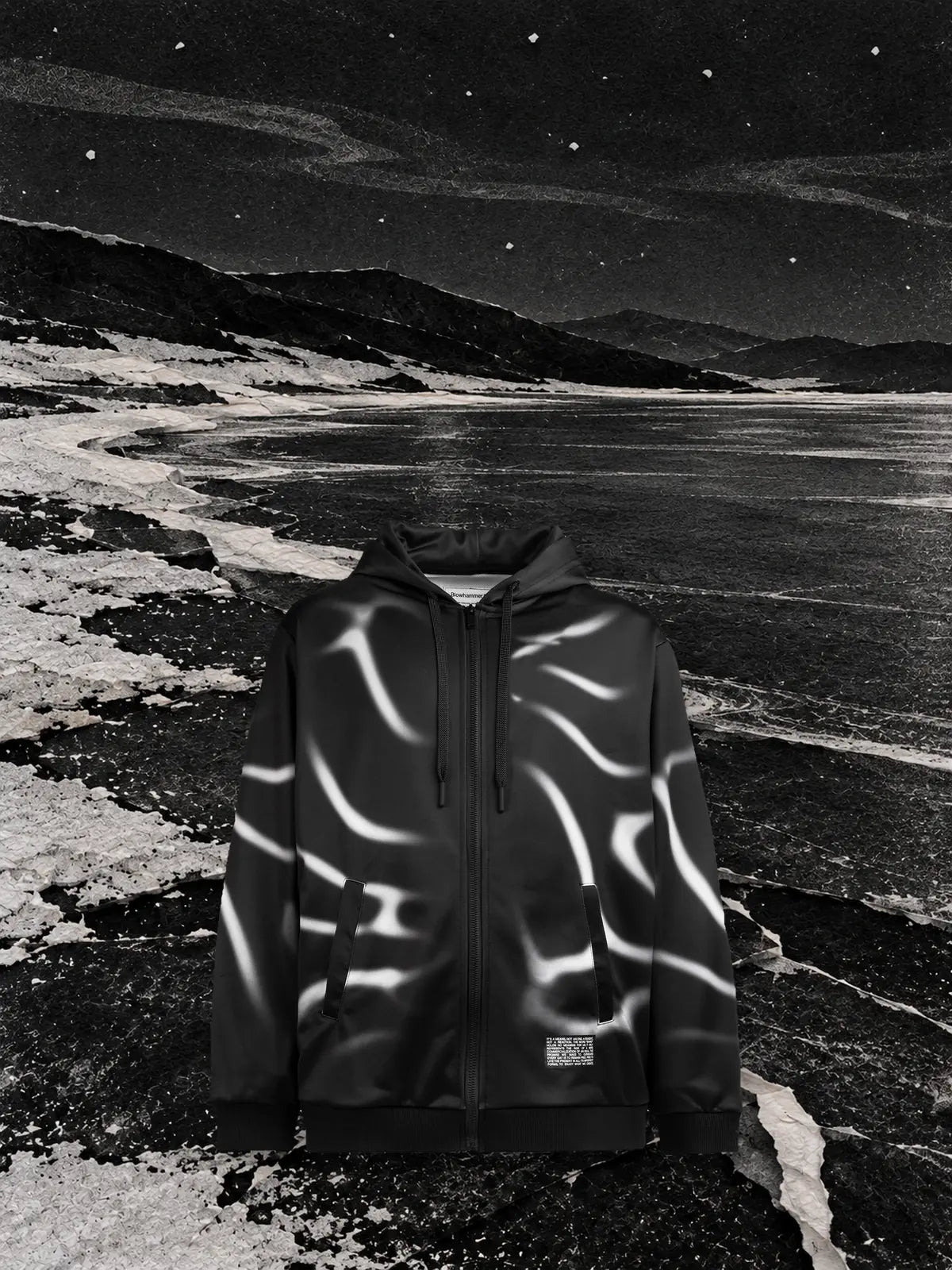 The black Tidegrey zip hoodie on a frozen black lake at night, with white reflections like the lines of the print.
