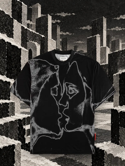 The black Unkiss Black t-shirt among cubes of torn white and black paper, under a grey sky.