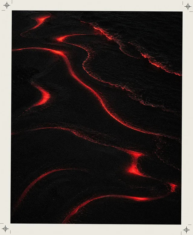 Uma costa preta vista de cima, de noite, com a orla das ondas que se acende de vermelho e desenha curvas desfocadas, como os rastos do estampado Tide.